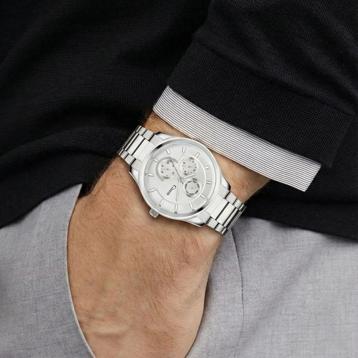 Silver analog wristwatch with chronograph dials on man's wrist, stainless steel band