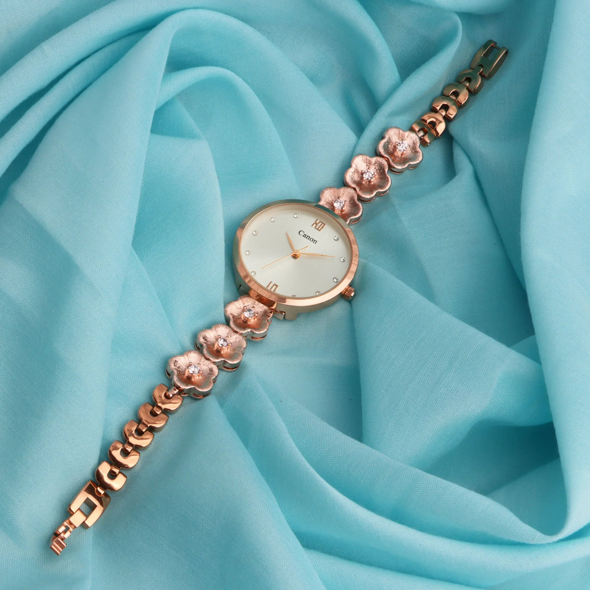 Elegant rose gold floral analog women's watch with crystal accents on light blue fabric