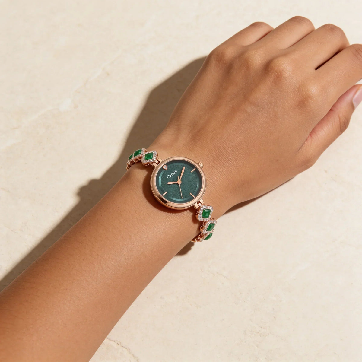 Elegant women’s analog watch with green dial and gem-studded rose gold bracelet on wrist