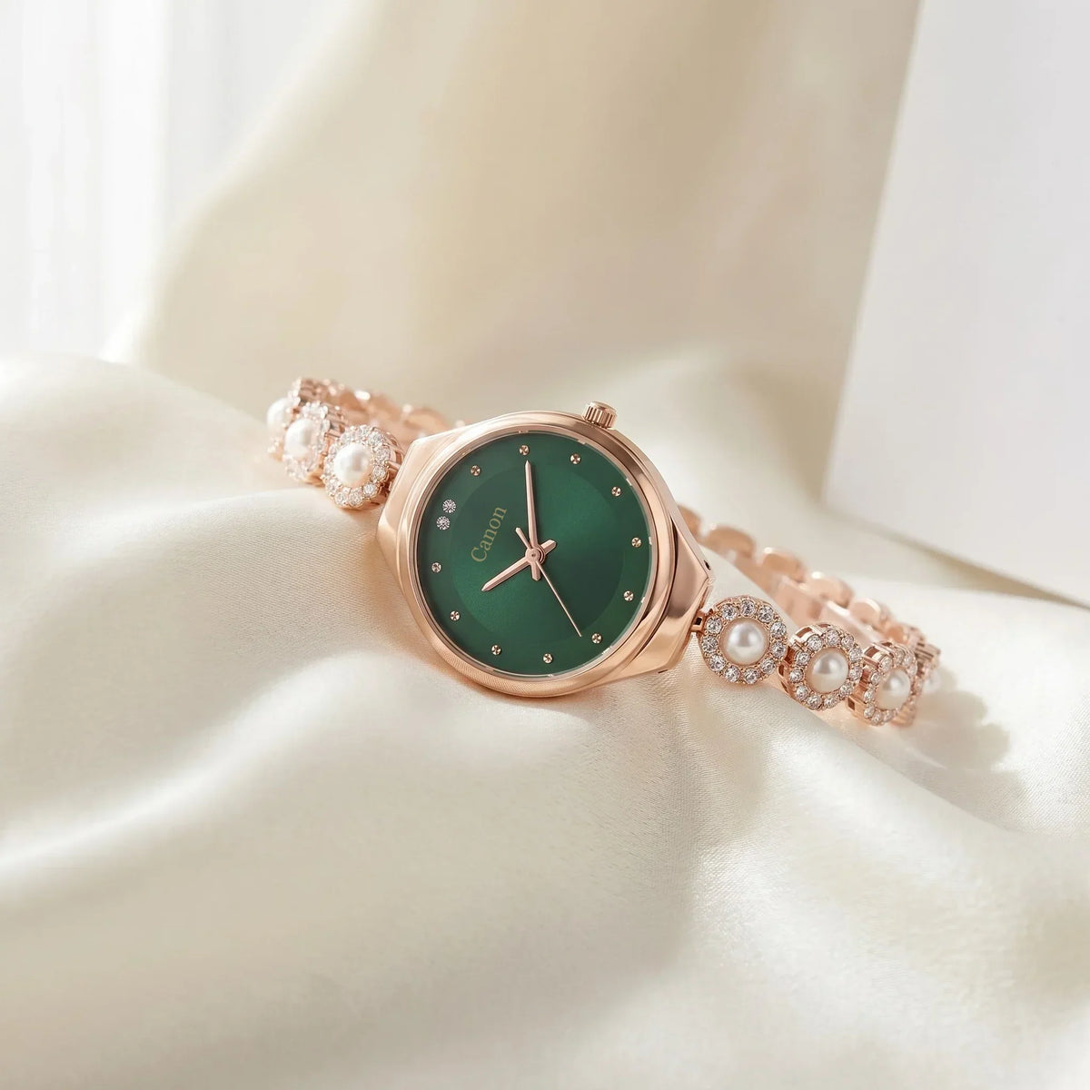 Elegant rose gold watch with green dial, pearl and crystal accents on soft fabric