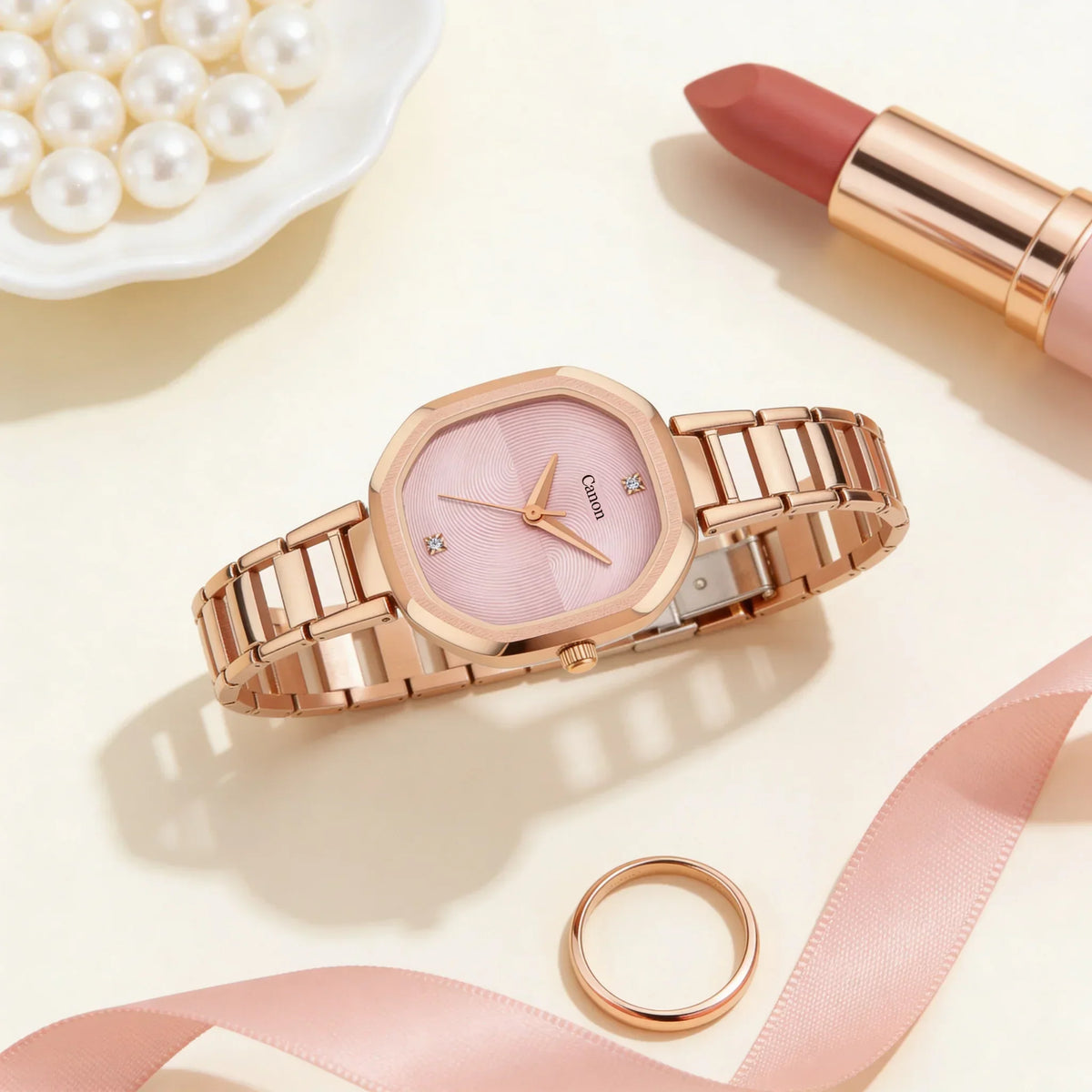 Rose gold women's analog watch with pink octagonal dial, next to lipstick and pearls