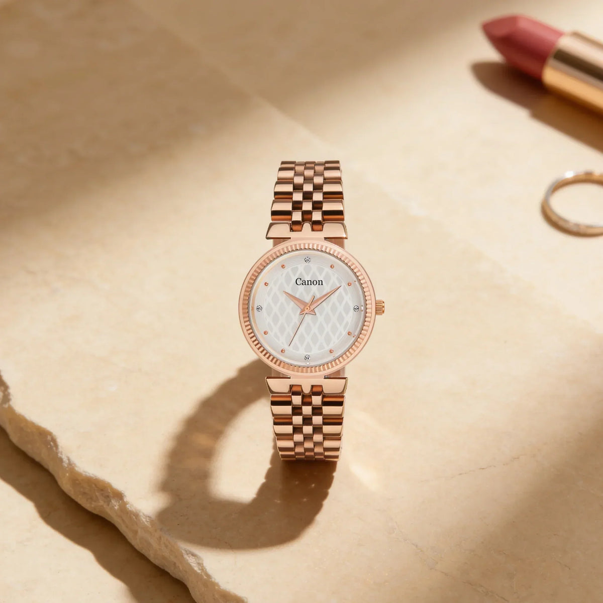 Elegant rose gold analog watch with patterned white dial on a stone surface, luxury women's accessory