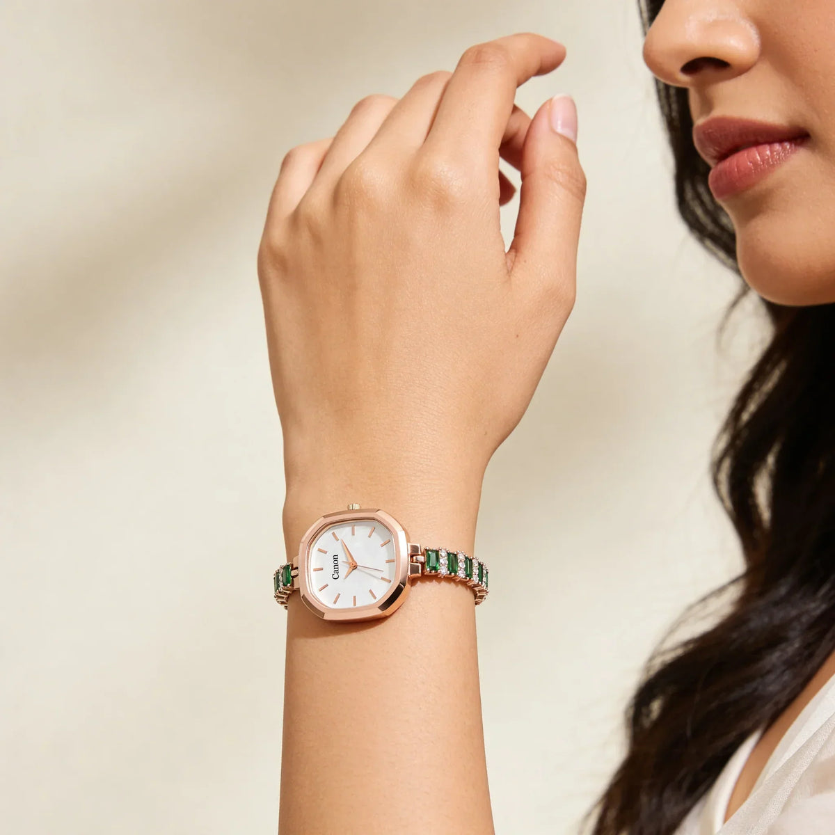 Woman wearing elegant analog wristwatch with green gemstone bracelet and rose gold case