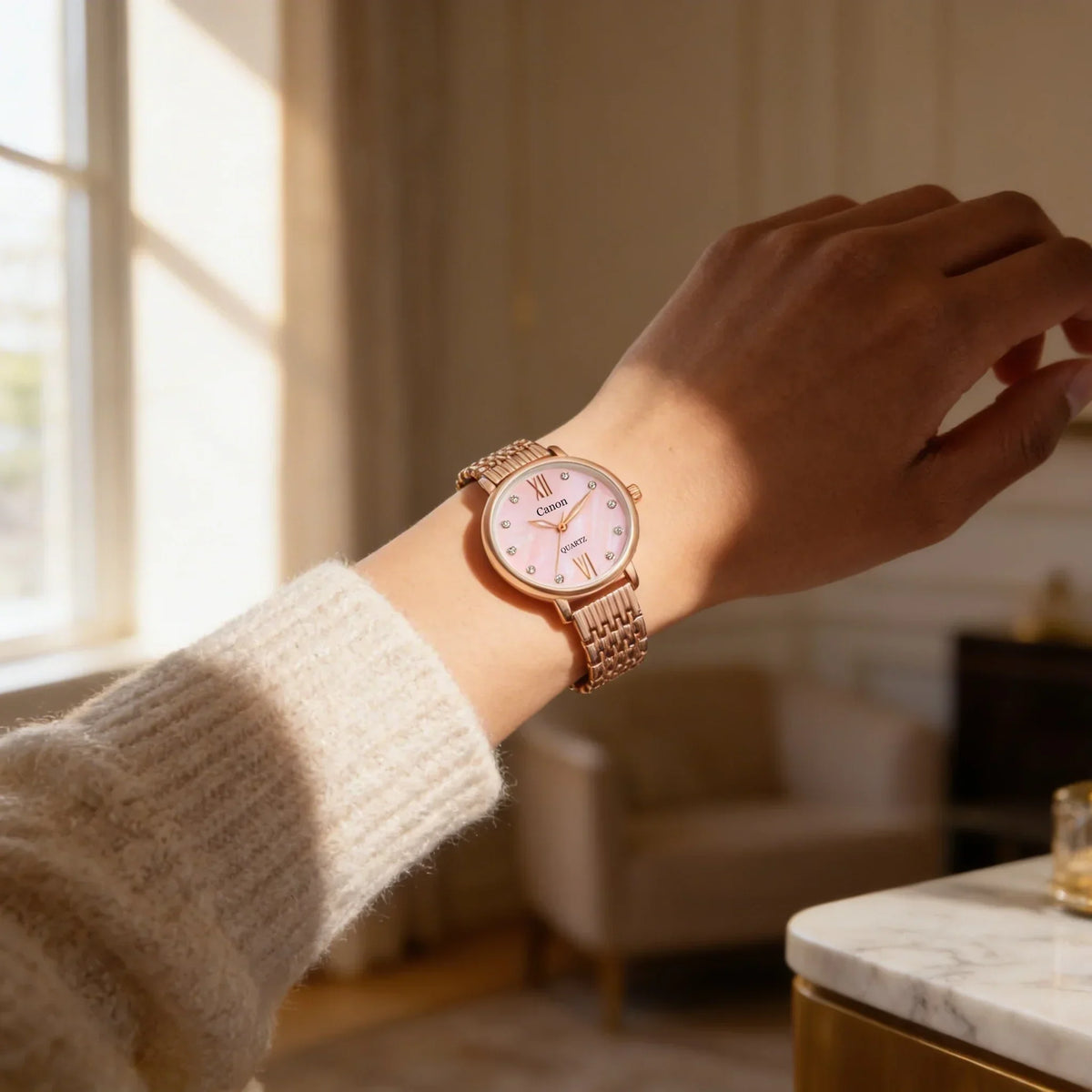 Rose gold analog wristwatch with pink dial and Roman numerals on a person's wrist indoors