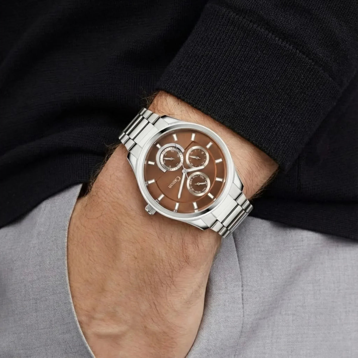 Men's analog watch with brown dial and silver metal strap on wrist