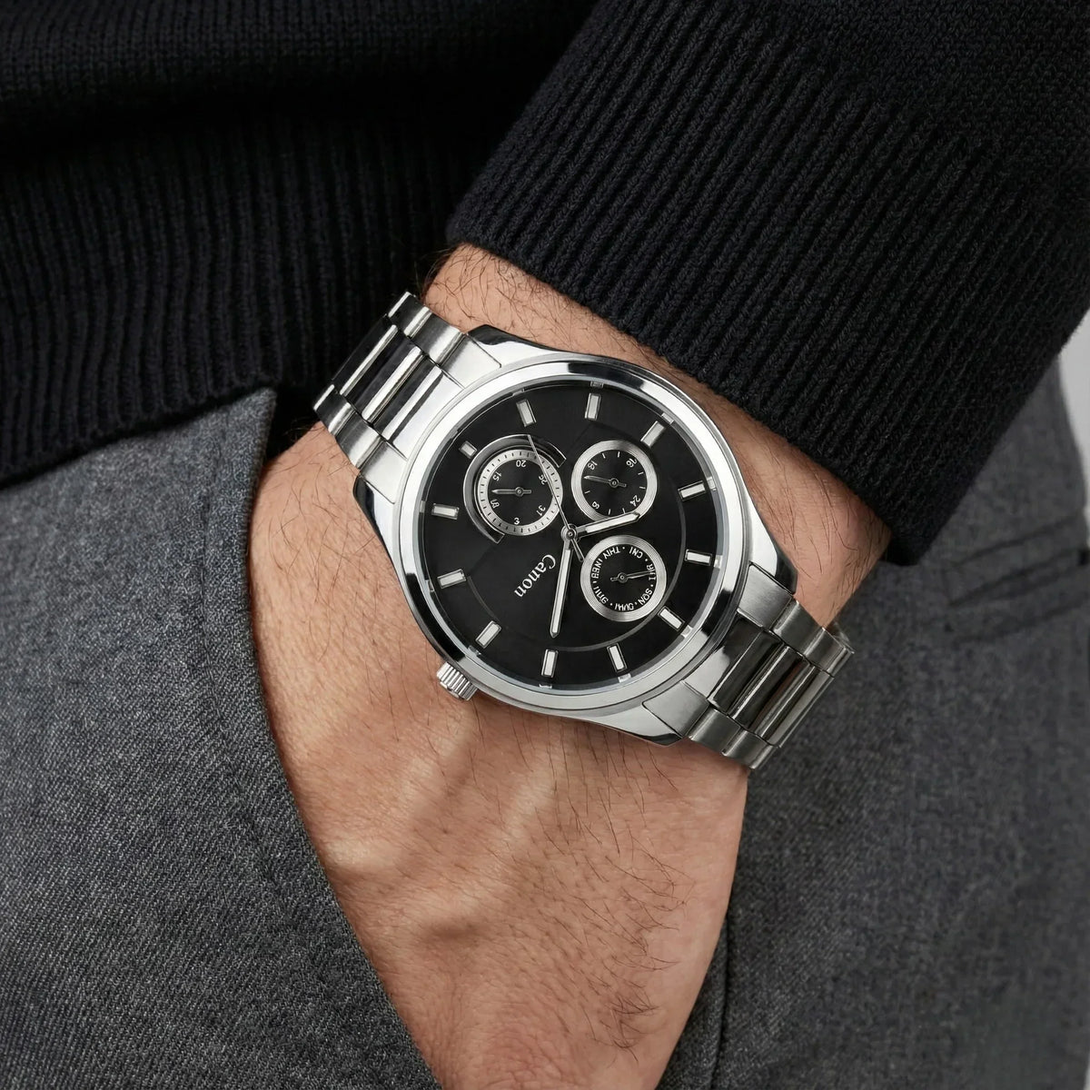 Men's silver analog wristwatch with black dial and three subdials on person's wrist
