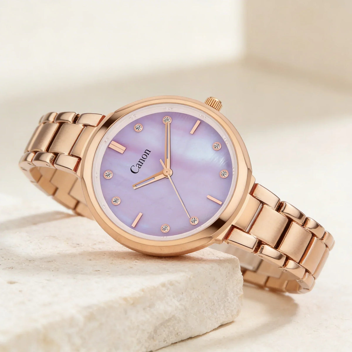 Rose gold analog watch with a lavender mother-of-pearl dial and crystal hour markers.