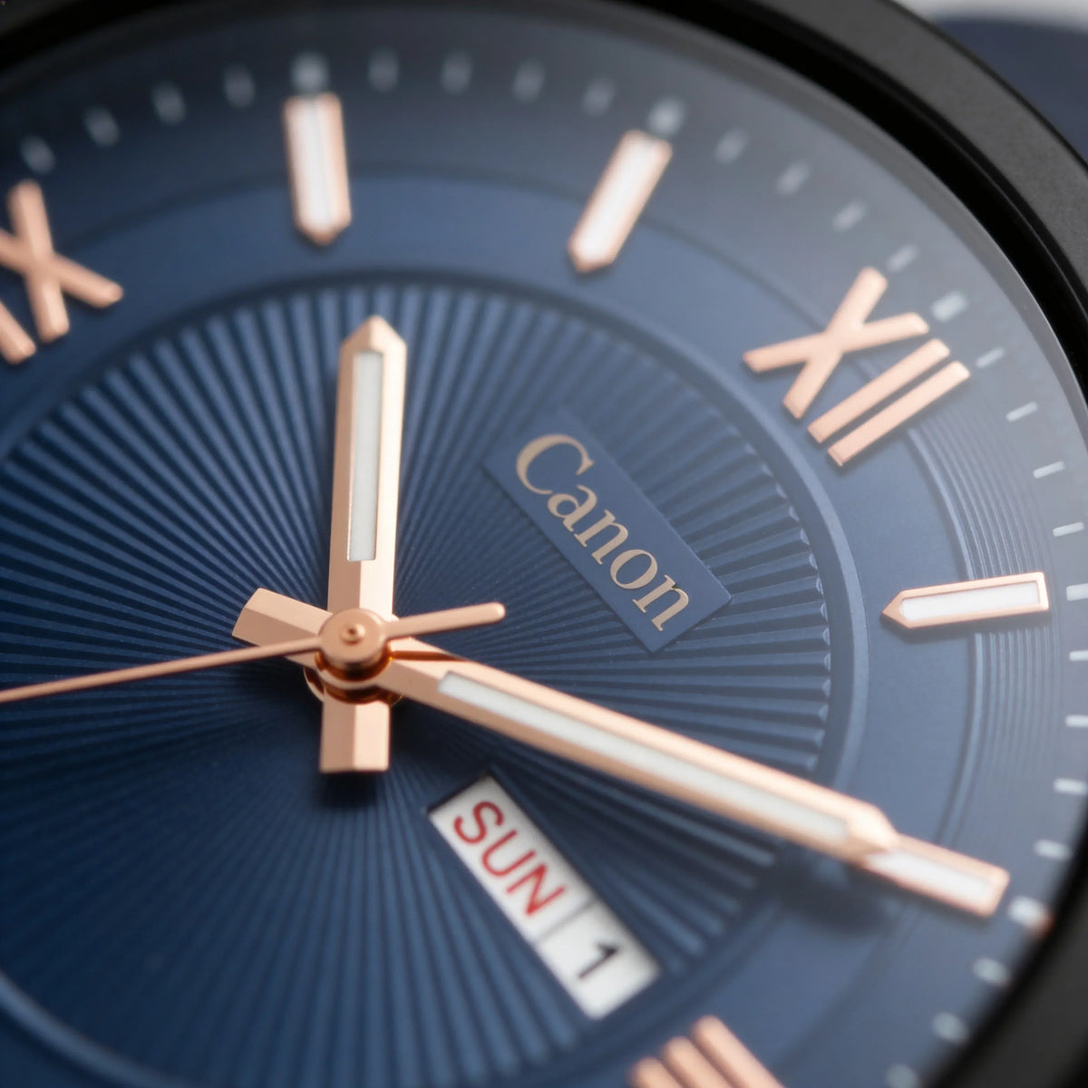 Close-up of blue analog watch face with rose gold hands and Roman numerals, day-date display
