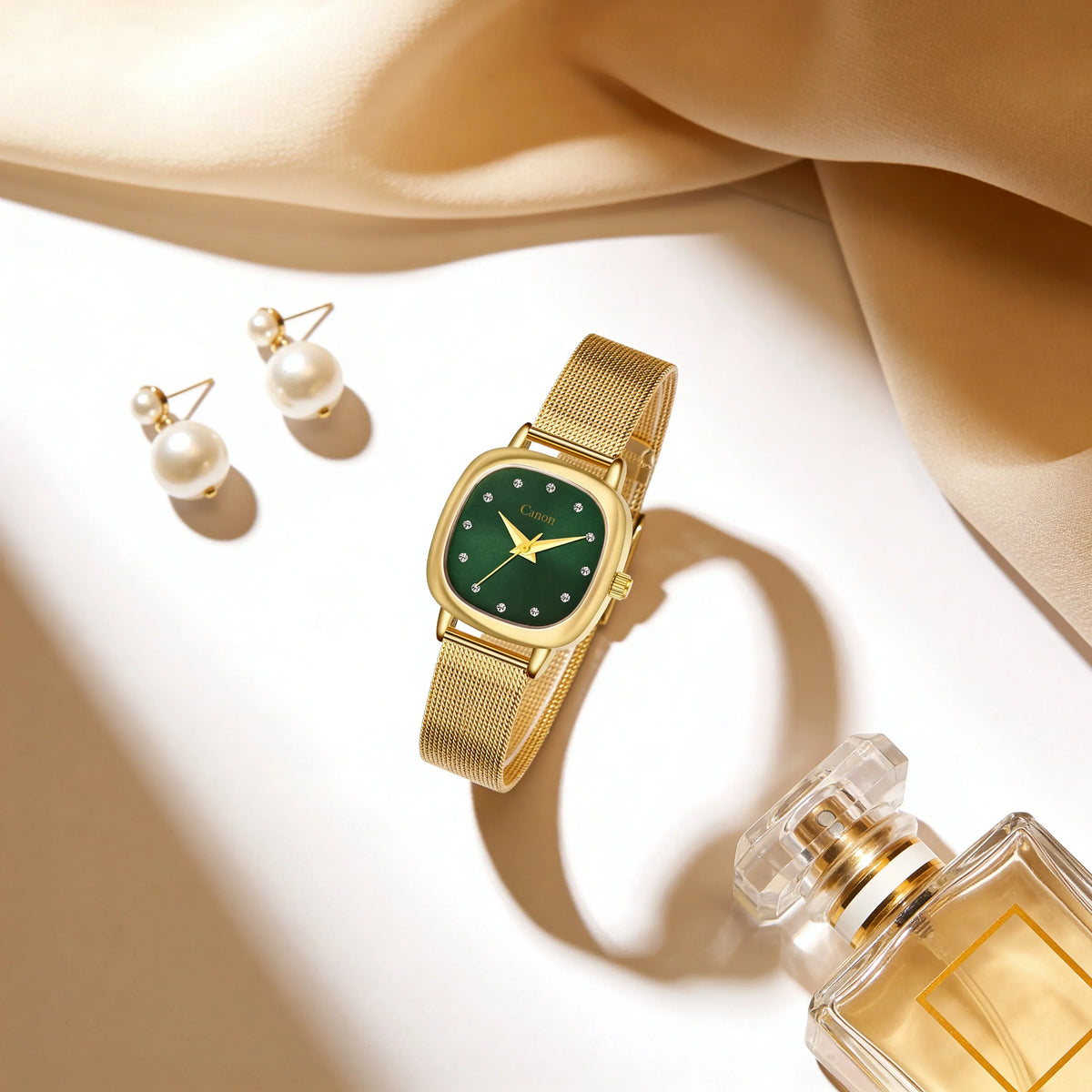 Elegant gold analog watch with green face, mesh strap, pearl earrings, and perfume bottle