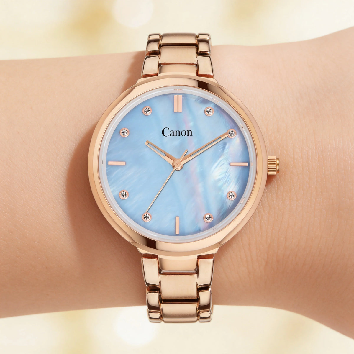 Rose gold analog watch with blue mother of pearl dial and crystal hour markers on wrist