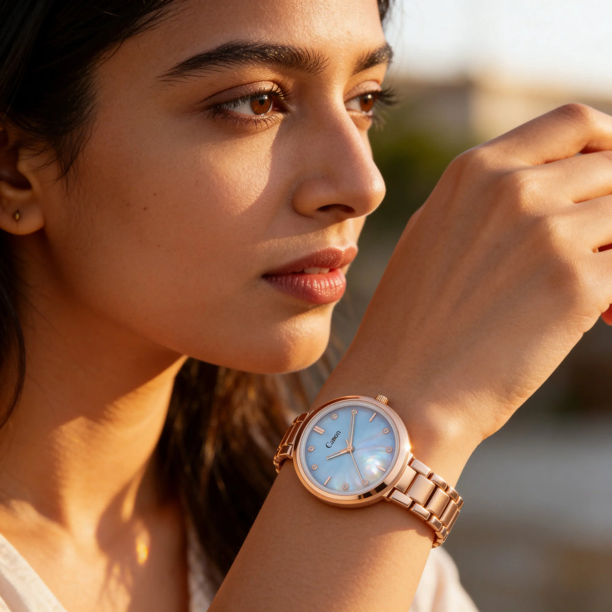 Woman wearing elegant rose gold analog wristwatch with blue dial in natural light