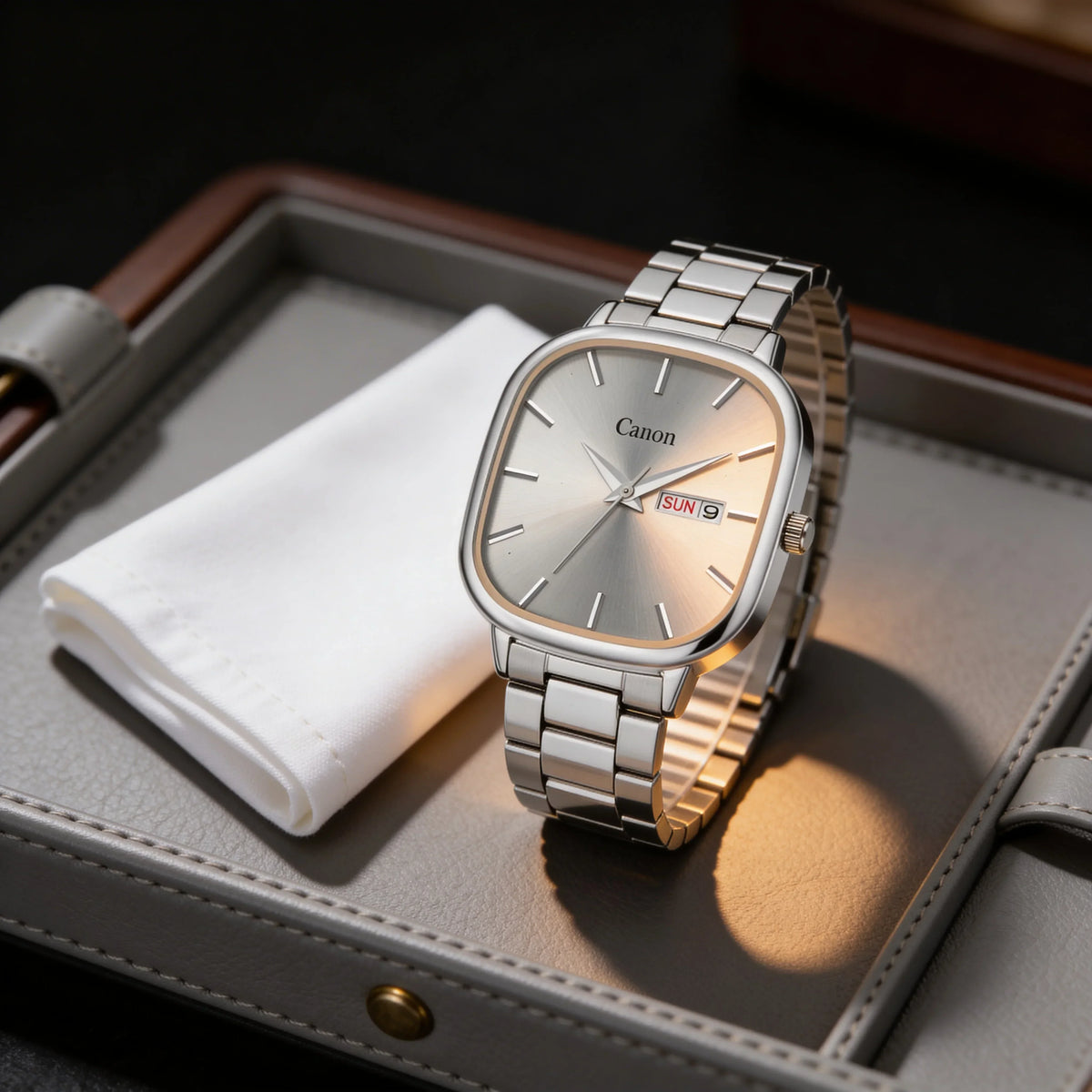 Silver analog wristwatch with metal band, day-date display on a watch tray, elegant design