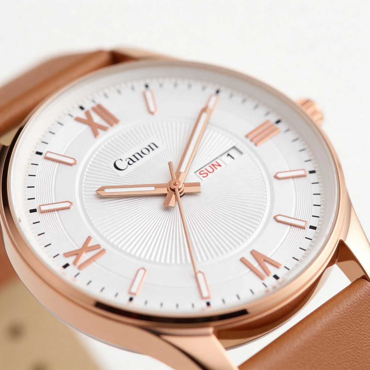 Rose gold analog watch with brown leather strap, white dial, Roman markers, and day-date display