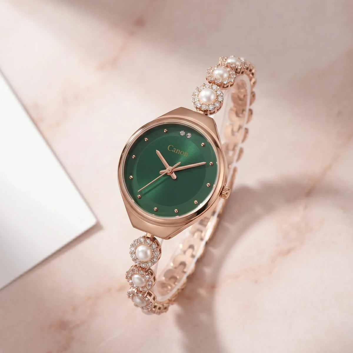Elegant rose gold watch with green dial, pearl & crystal accents on marble