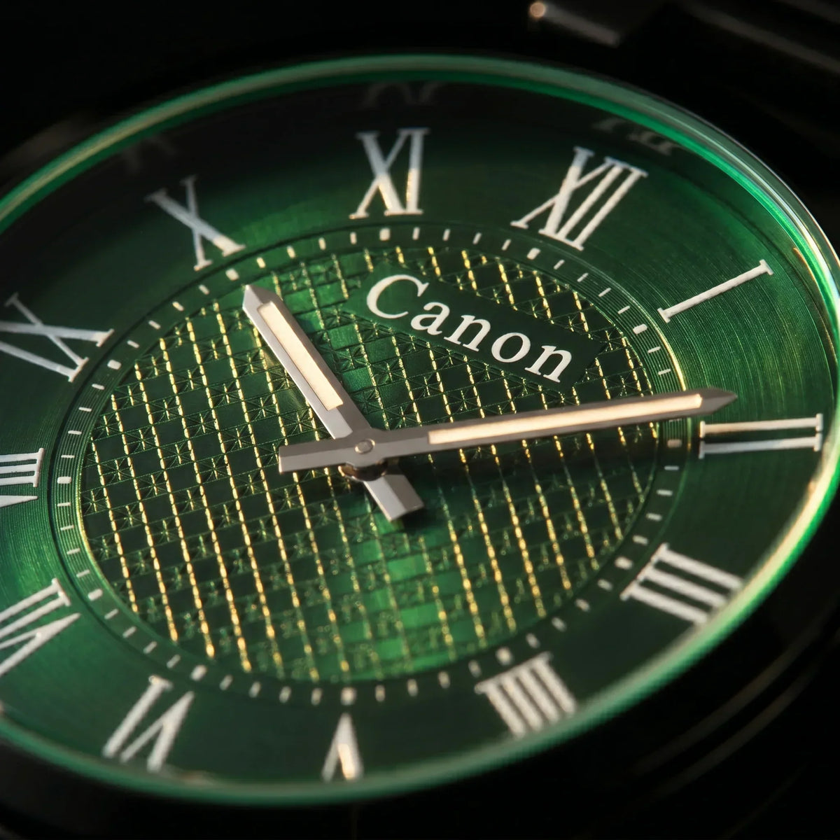 Elegant green dial watch with Roman numerals and Canon branding, showcasing timeless design.