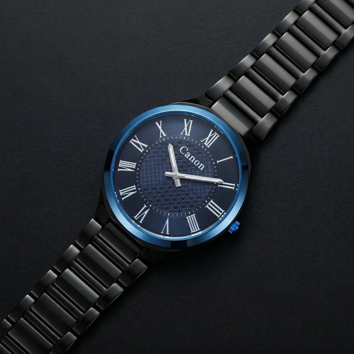 Canon analog watch with black metal band, blue dial, Roman numerals, and date window on dark background