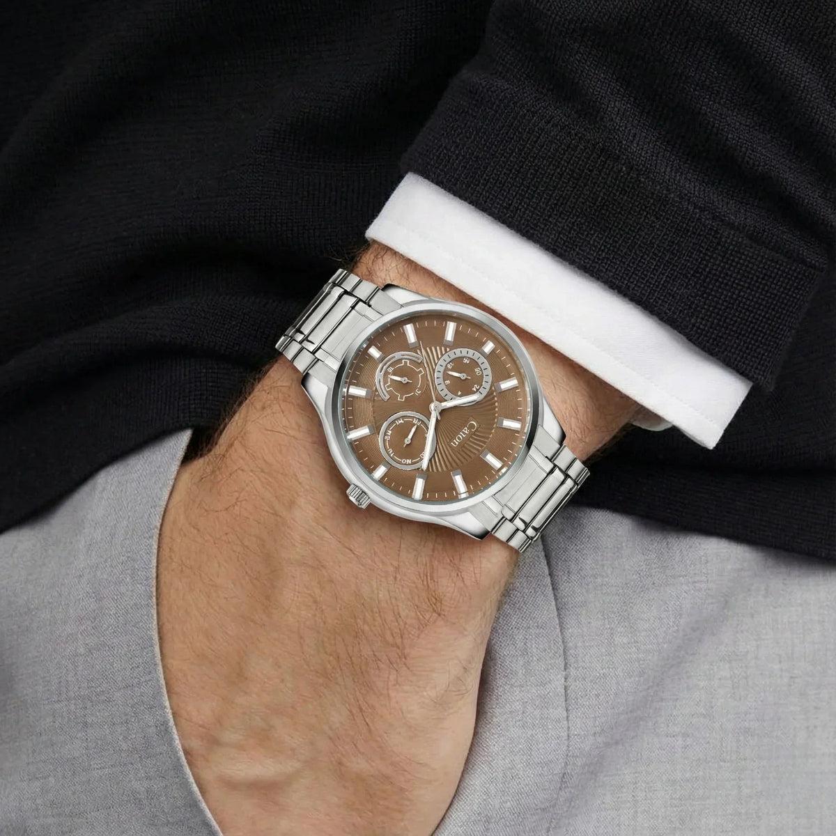 Men's analog watch with brown dial, silver markers, subdials, and metal band on wrist