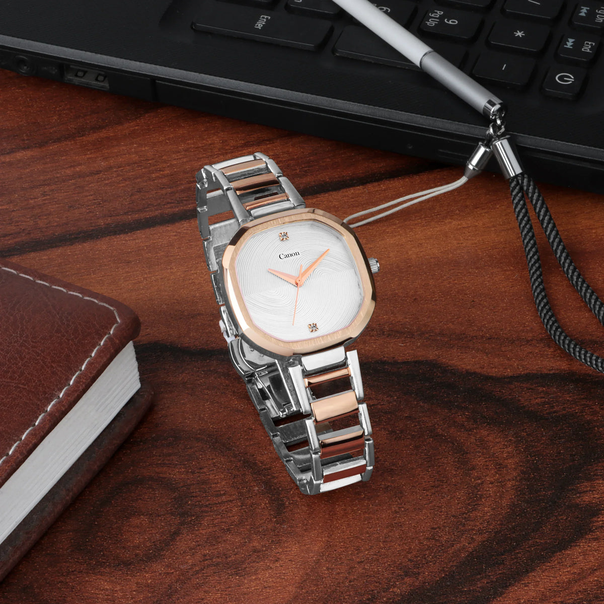 Elegant women's analog wrist watch with silver and rose gold band on wooden desk