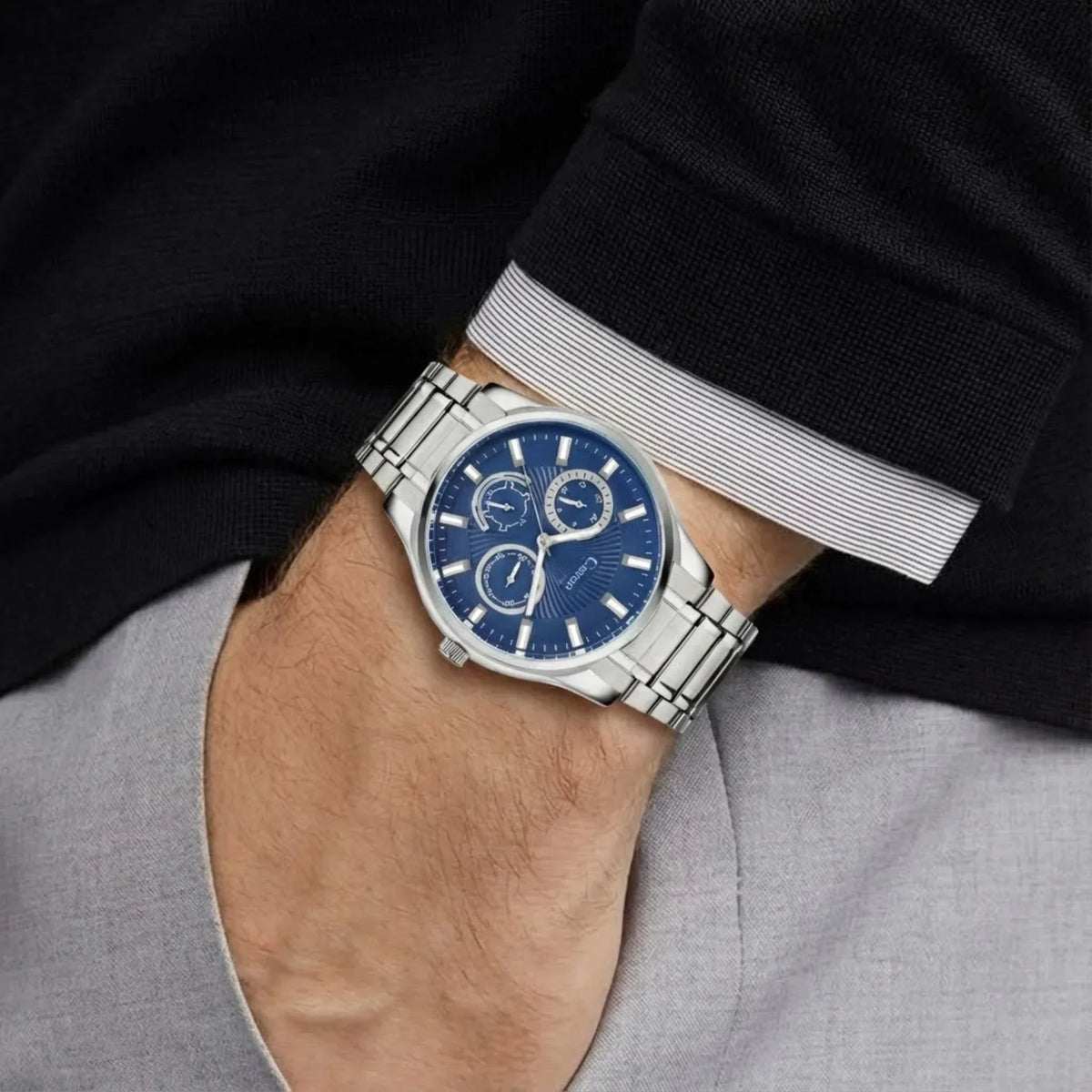 Men's analog wristwatch with blue dial and silver metal band on wrist