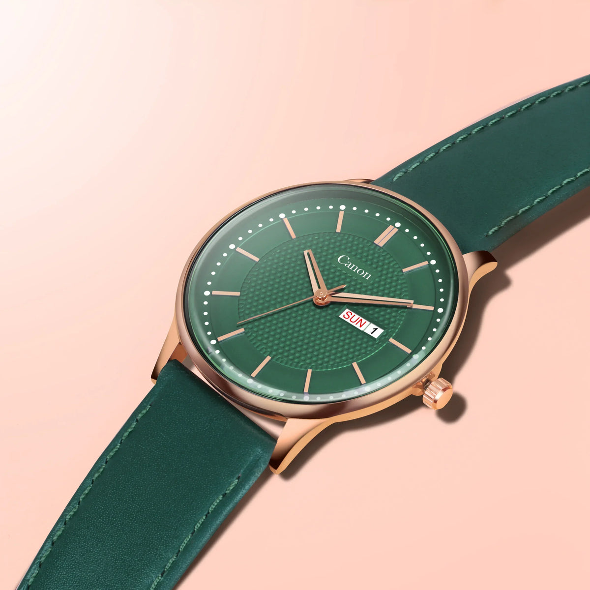 Green analog wristwatch with gold case, day and date display, on a peach background