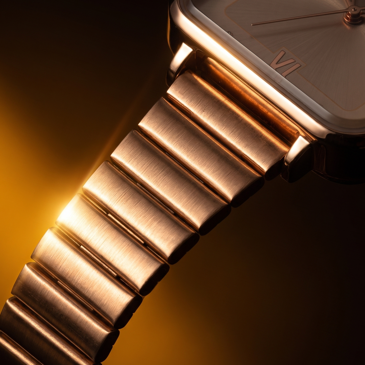 Rose gold analog quartz watch with brushed metal bracelet and Roman numeral VI, warm studio lighting
