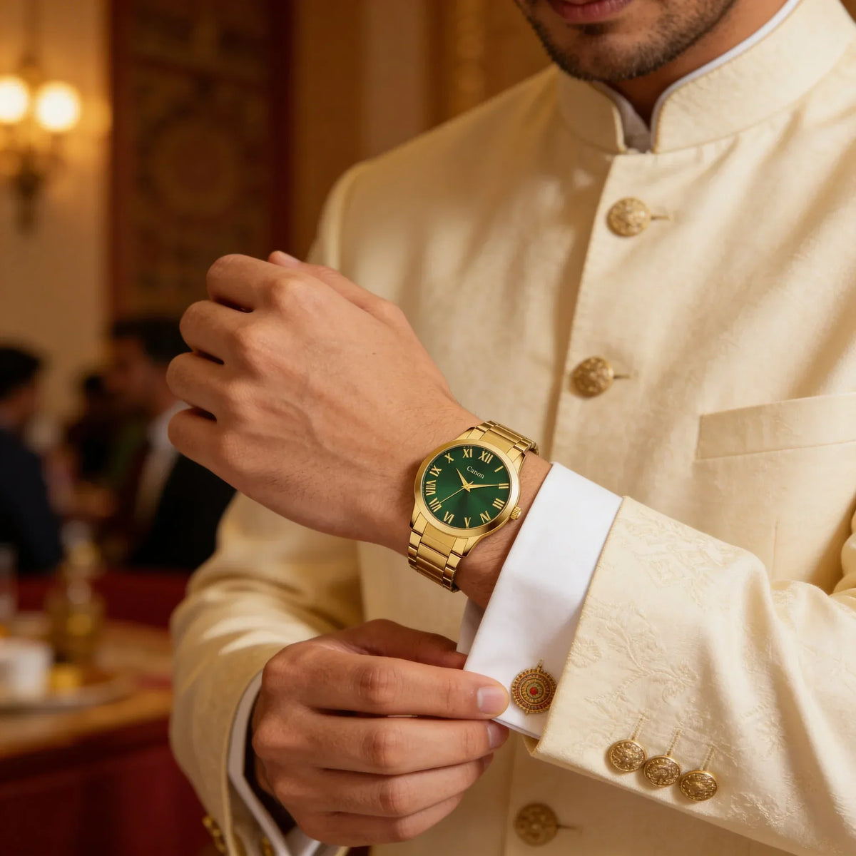 Elegant gold quartz watch with green dial and Roman numerals on man's wrist in formal attire