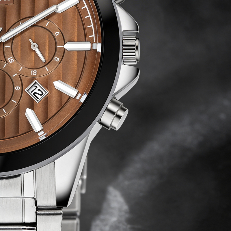 Close-up of a silver analog watch with a brown dial, date display, and metal bracelet