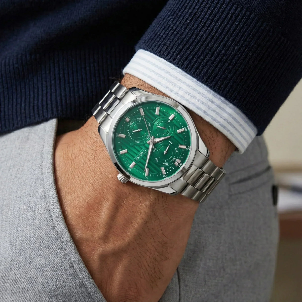 Men’s silver analog wristwatch with green dial and chronograph on wrist, classic style