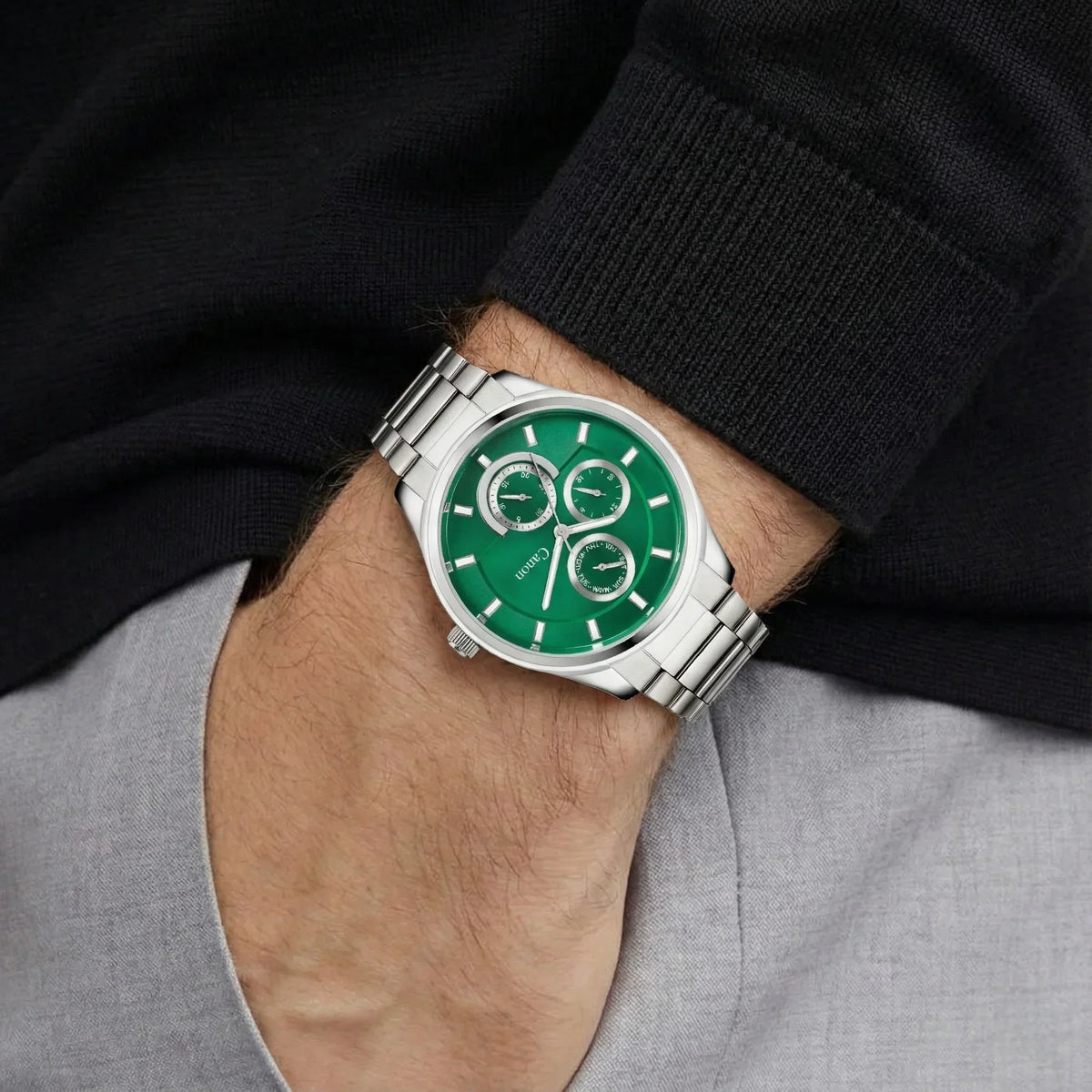 Men’s silver analog wristwatch with green dial and chronograph features on wrist