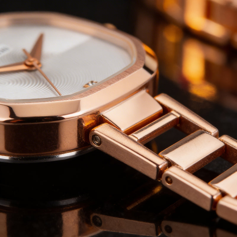 Close-up of rose gold analog watch with metal bracelet on black surface