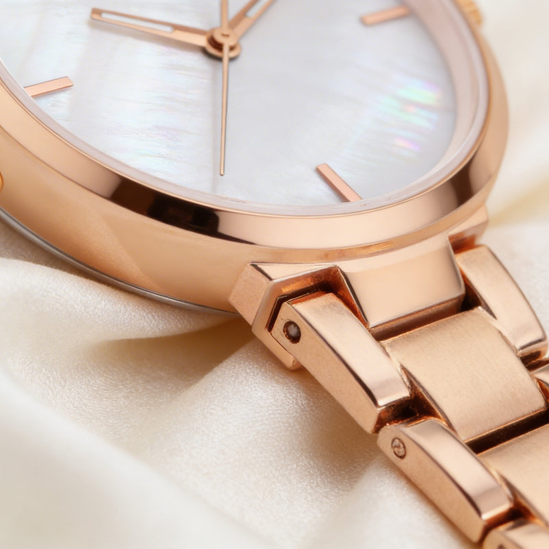 Close-up of rose gold analog watch with metal band and white mother-of-pearl dial