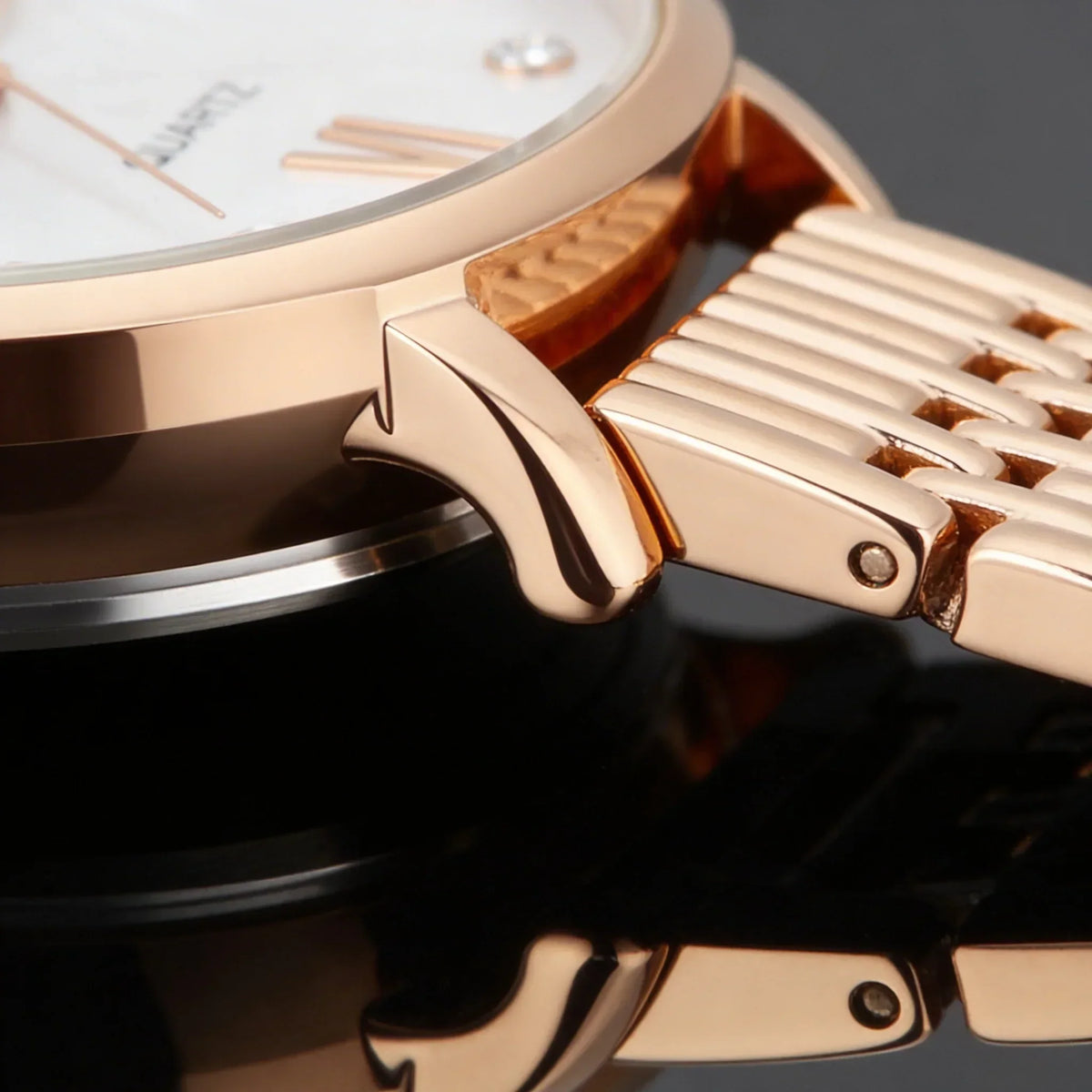 Close-up of a rose gold analog watch with linked metal band and minimalist design
