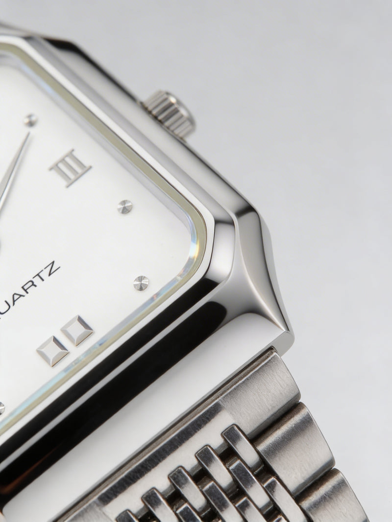 Close-up of a silver analog quartz watch with Roman numerals and metal link strap.