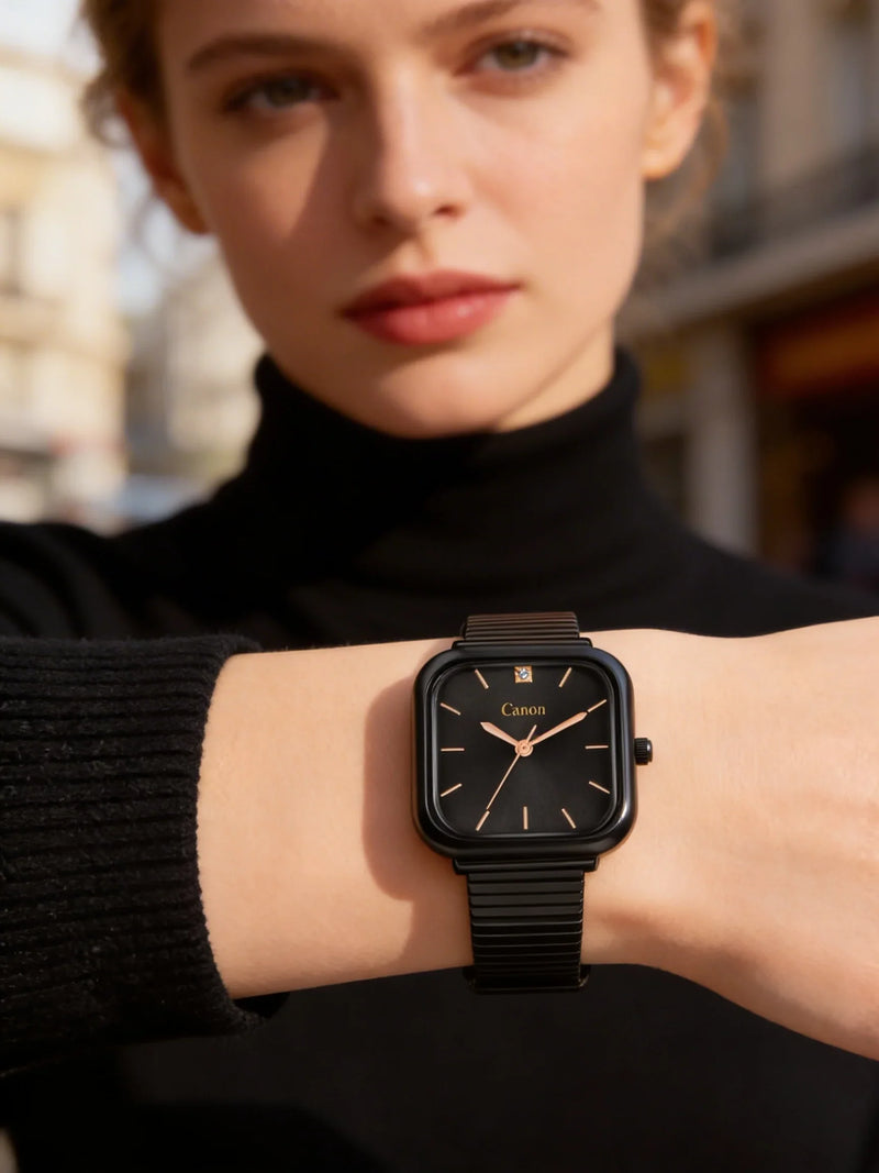 Woman wearing a black square analog watch with gold details, stylish outdoor setting