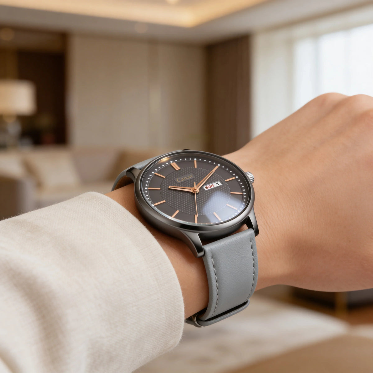 Analog wristwatch with black dial, rose gold markers, and grey leather strap on wrist indoors