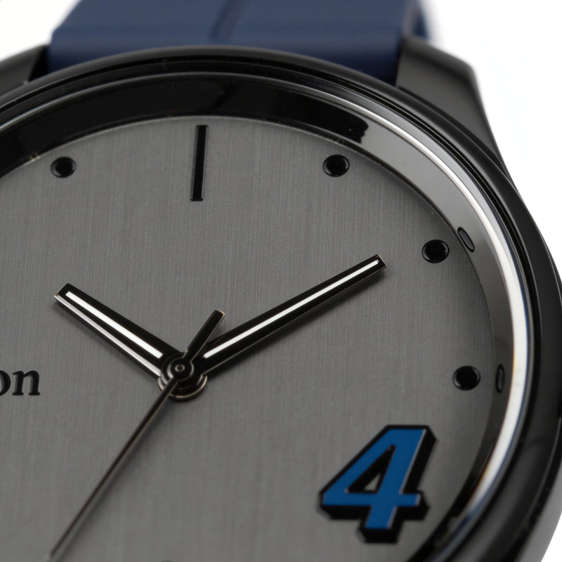 Close-up of a men's analog wristwatch with a grey dial, black markers, and blue number 4.