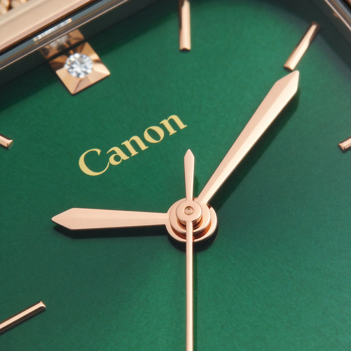 Close-up of gold analog watch hands on a green dial with minimalist markers