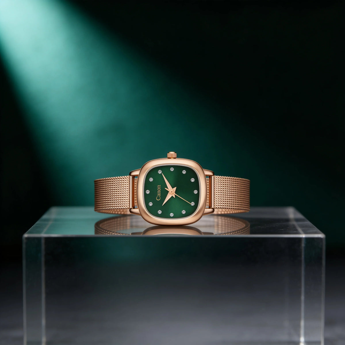 Elegant rose gold watch with green dial and diamond markers, displayed on acrylic stand against dark green backdrop