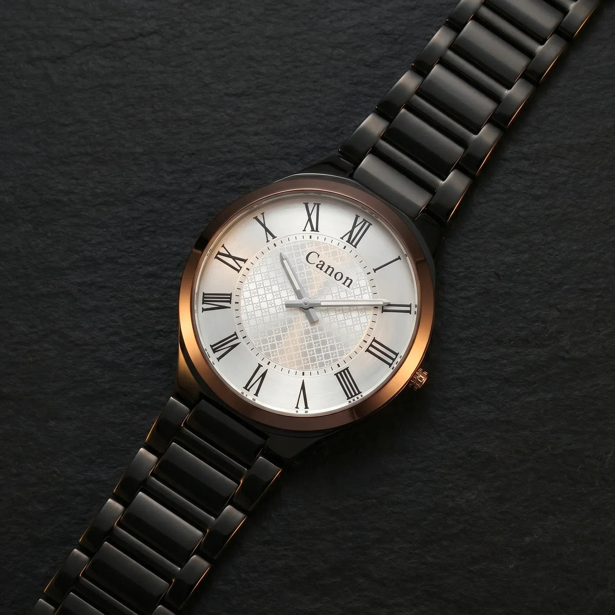Elegant analog watch with Roman numerals, rose gold case, black link bracelet, and white dial on dark slate.
